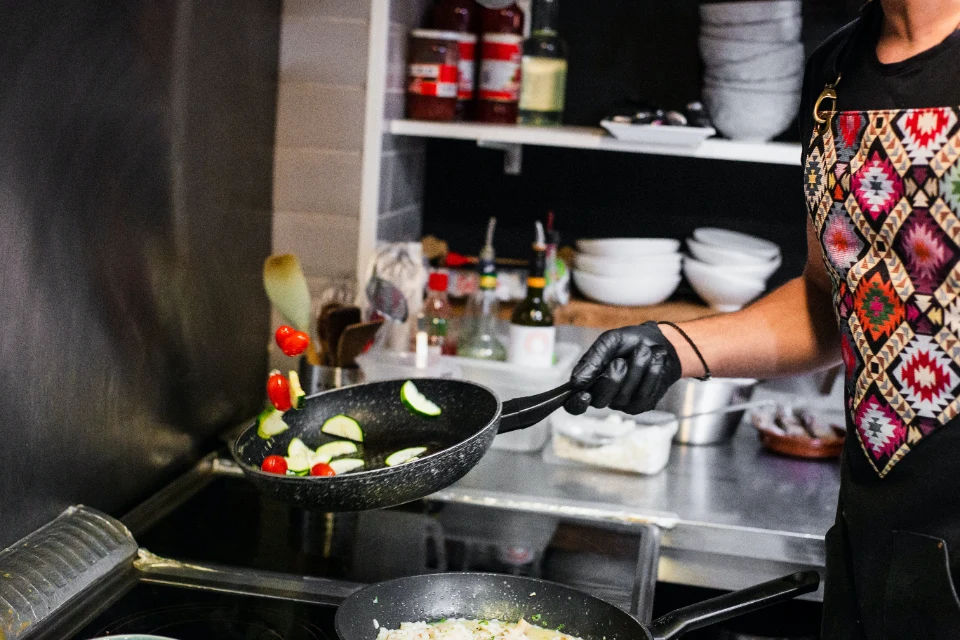 A cook tossing vegetables in a frying pan