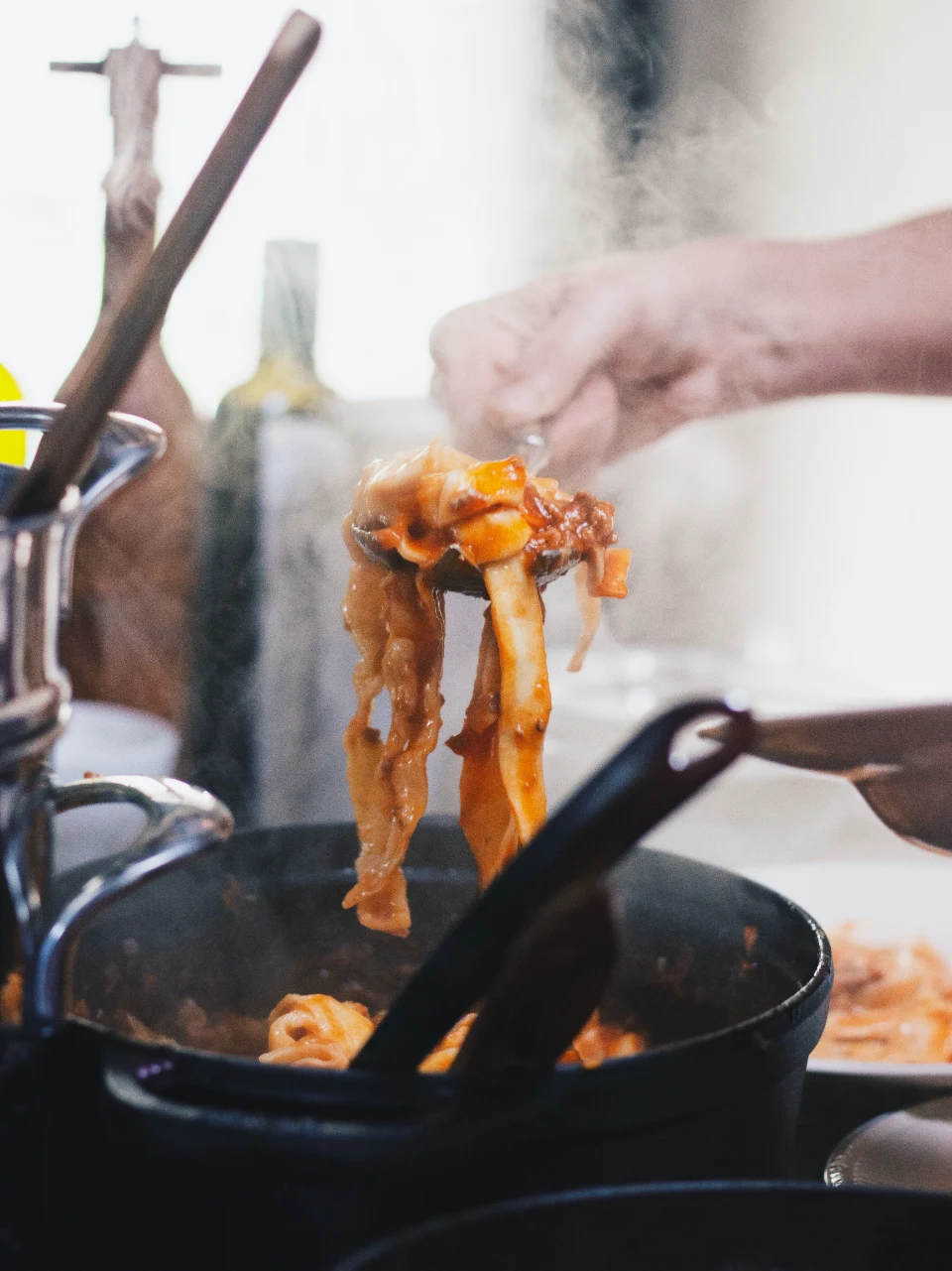 Noodles being lifted from a wok with chopsticks